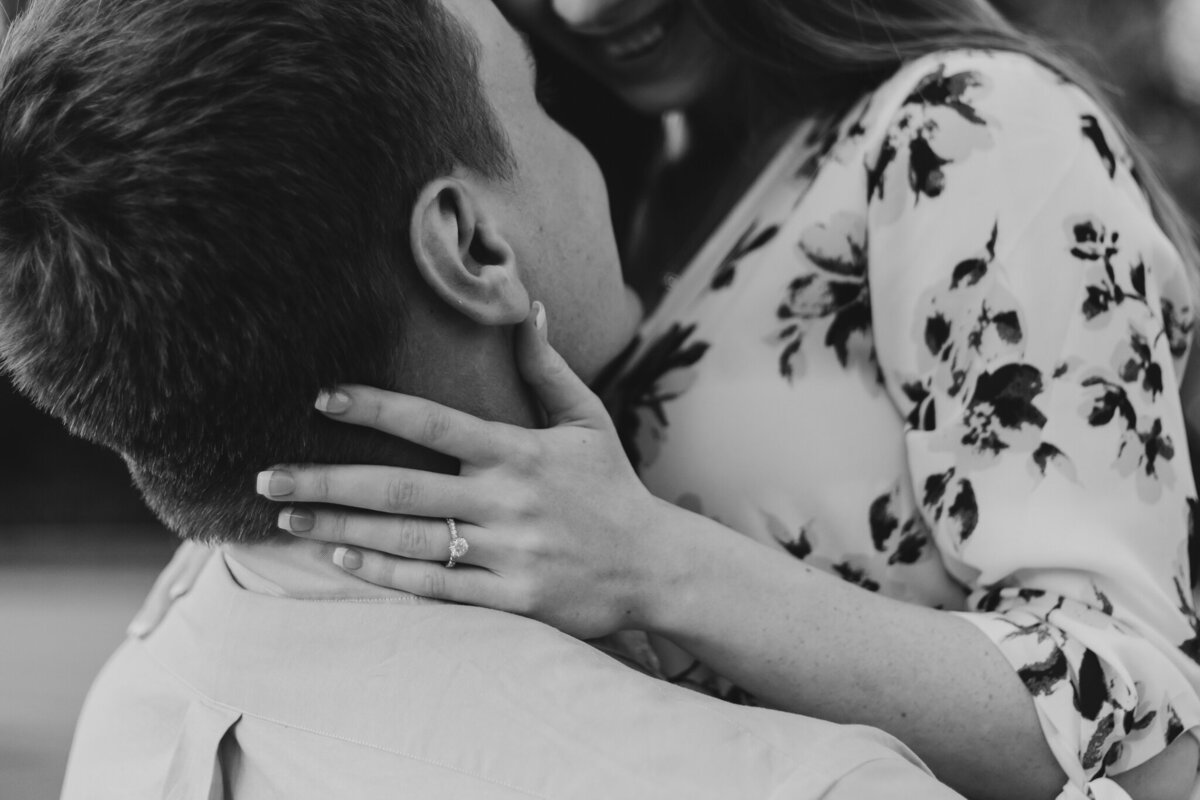 Close-up of Craig and Emily sharing a romantic moment during their engagement session at Dandelion Fountain in Downtown Houston, Texas. Emily’s hand rests gently on Craig’s shoulder, showcasing her engagement ring while they smile intimately.