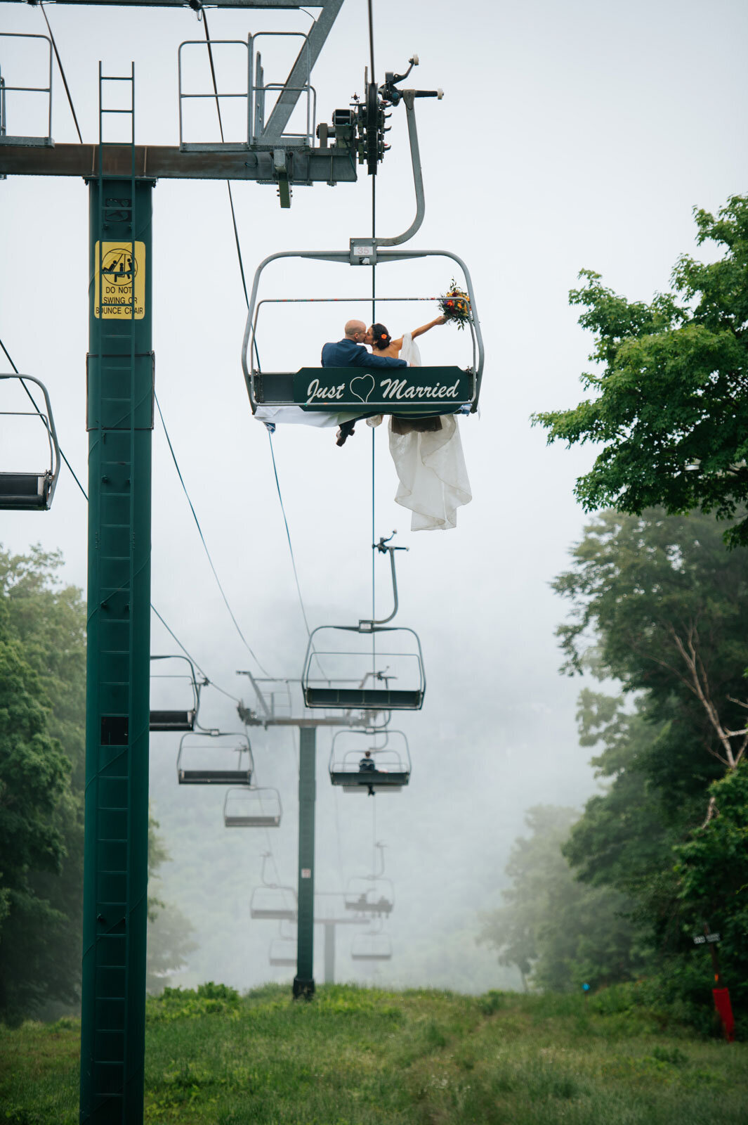 bride and groom riding on ski chairlift with just married sign at sugarbush resort wedding