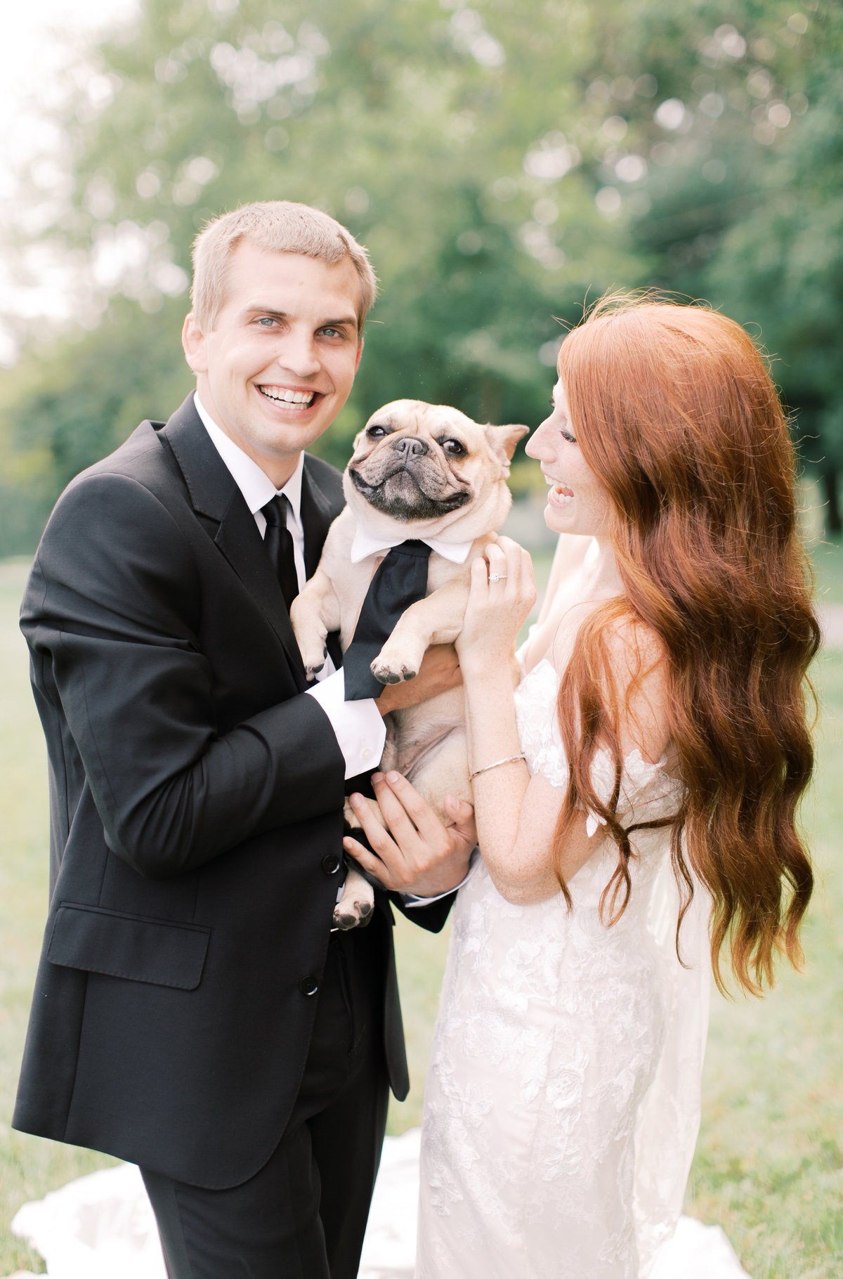 bride and groom holding pet pug dressed in wedding attire