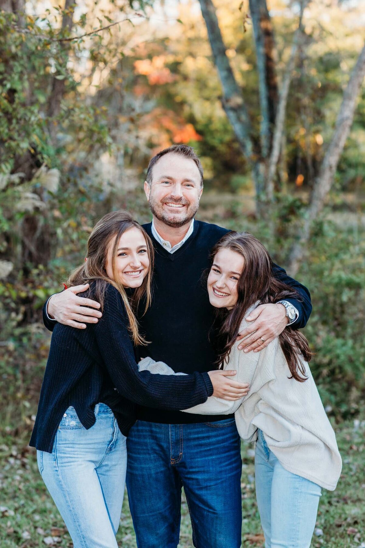 A dad and his two daughters hugging for the camera at their family portraits.