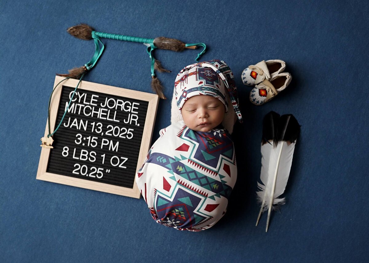 Mom and Dad kissing newborn baby with white light behind them.