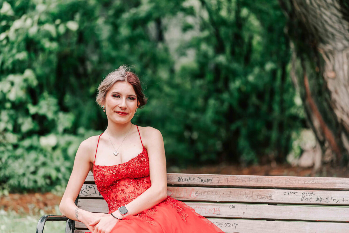 A waist up image of a girl sitting on a bench. 