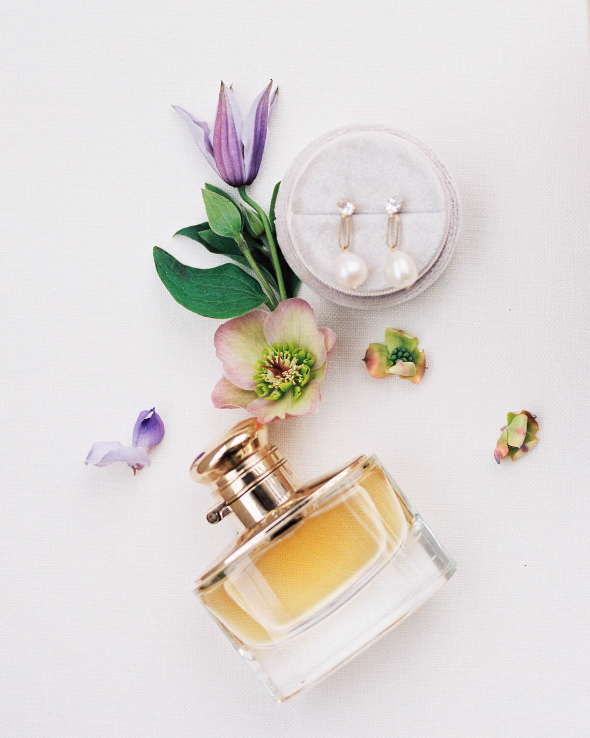 A stylized photo of a brides perfume and earrings.