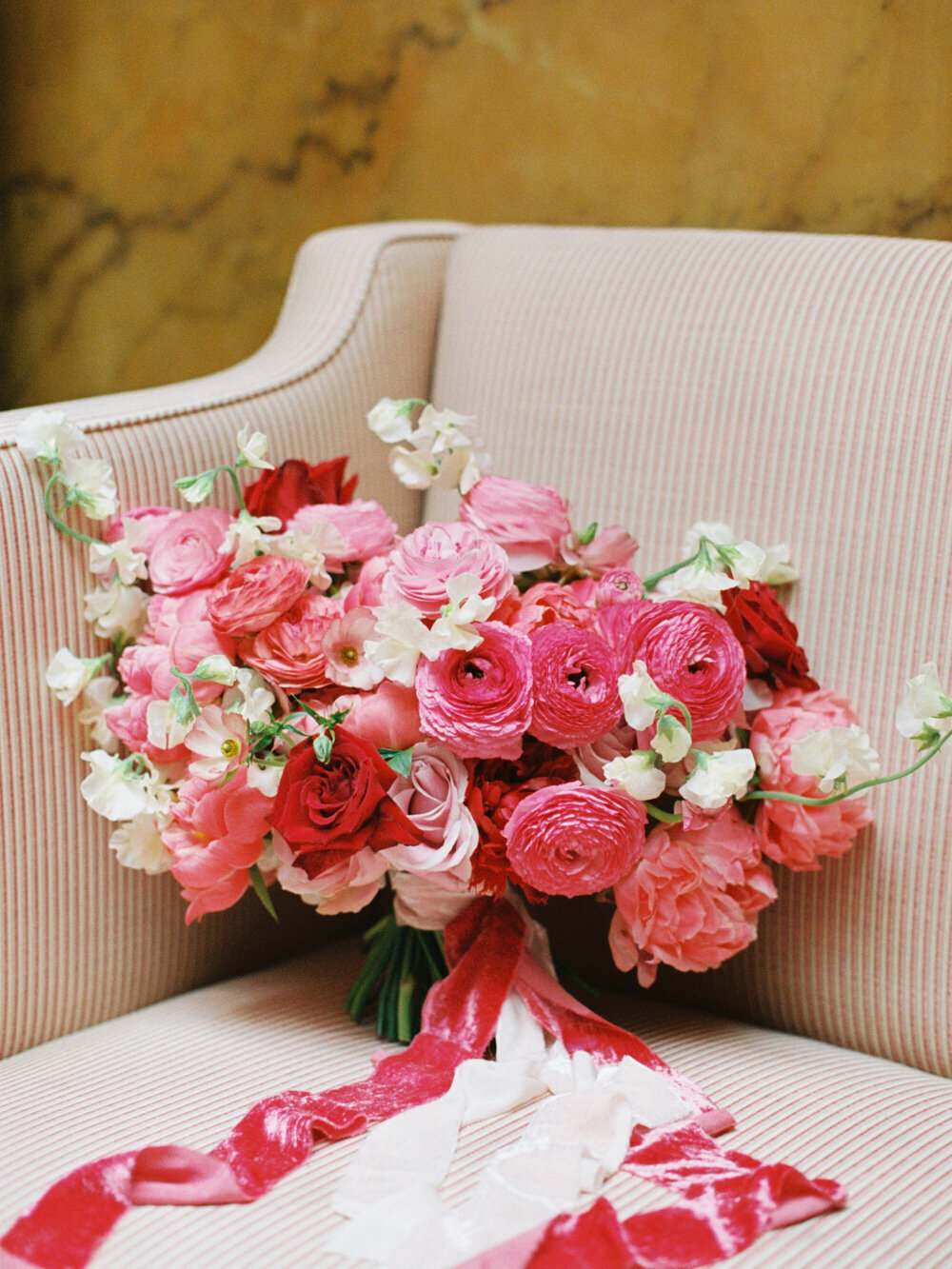 red colour bride flower bouquet captured on the sofa with velvet ribbons