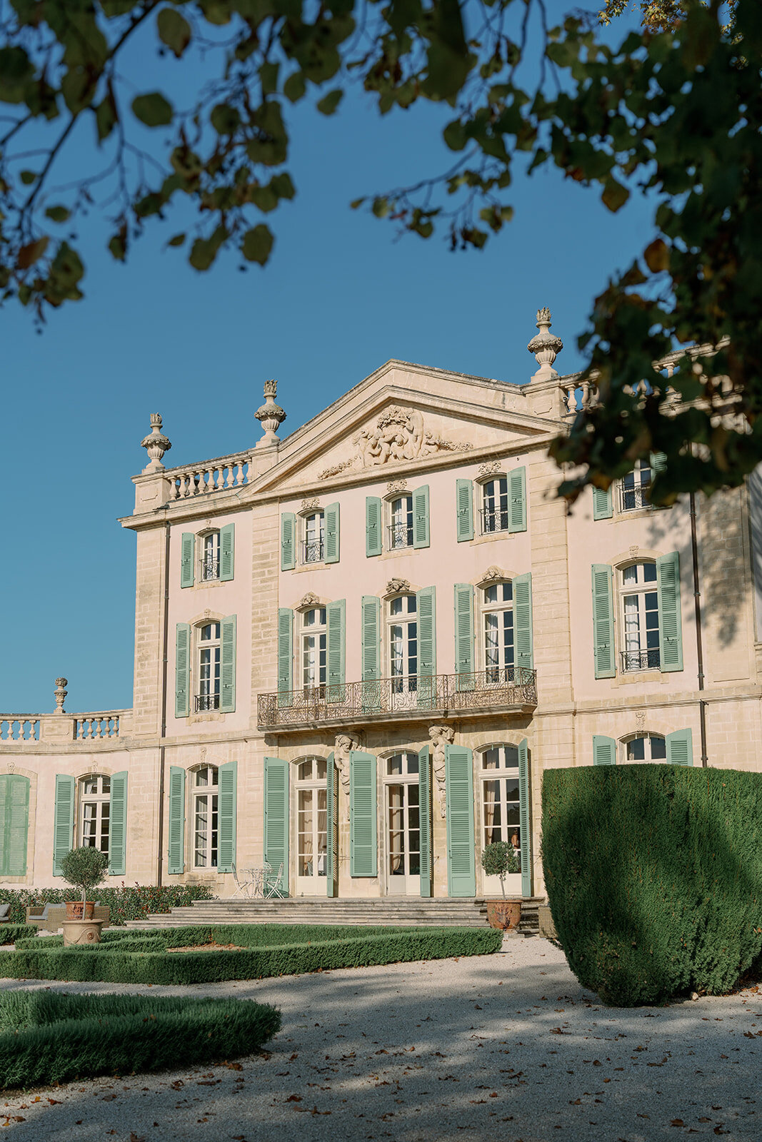 Grand exterior of Château de Tourreau with mint shutters, symmetrical windows, and manicured French gardens.