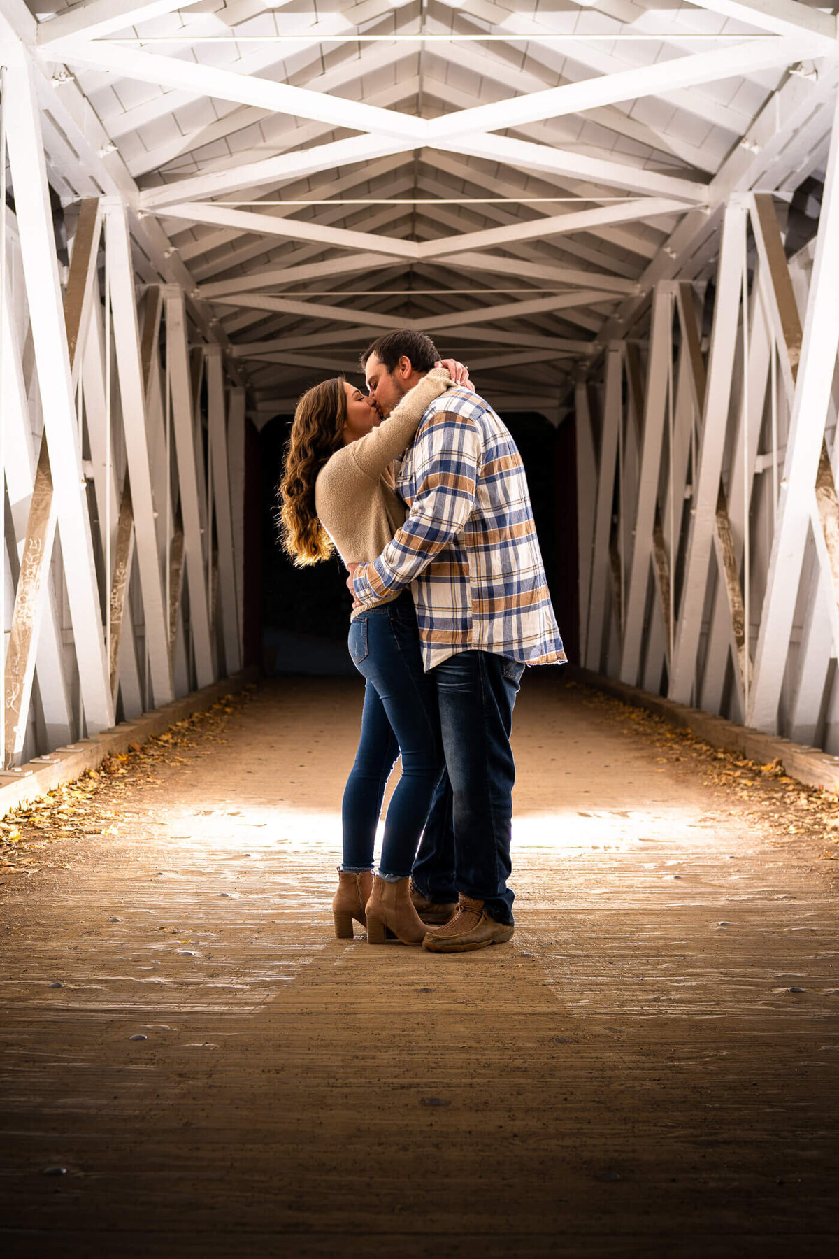Dramatic Pittsburgh engagement photography of couple kissing under the covered bridge at McConnell's Mill State Park. Lit by flash and natural light.
