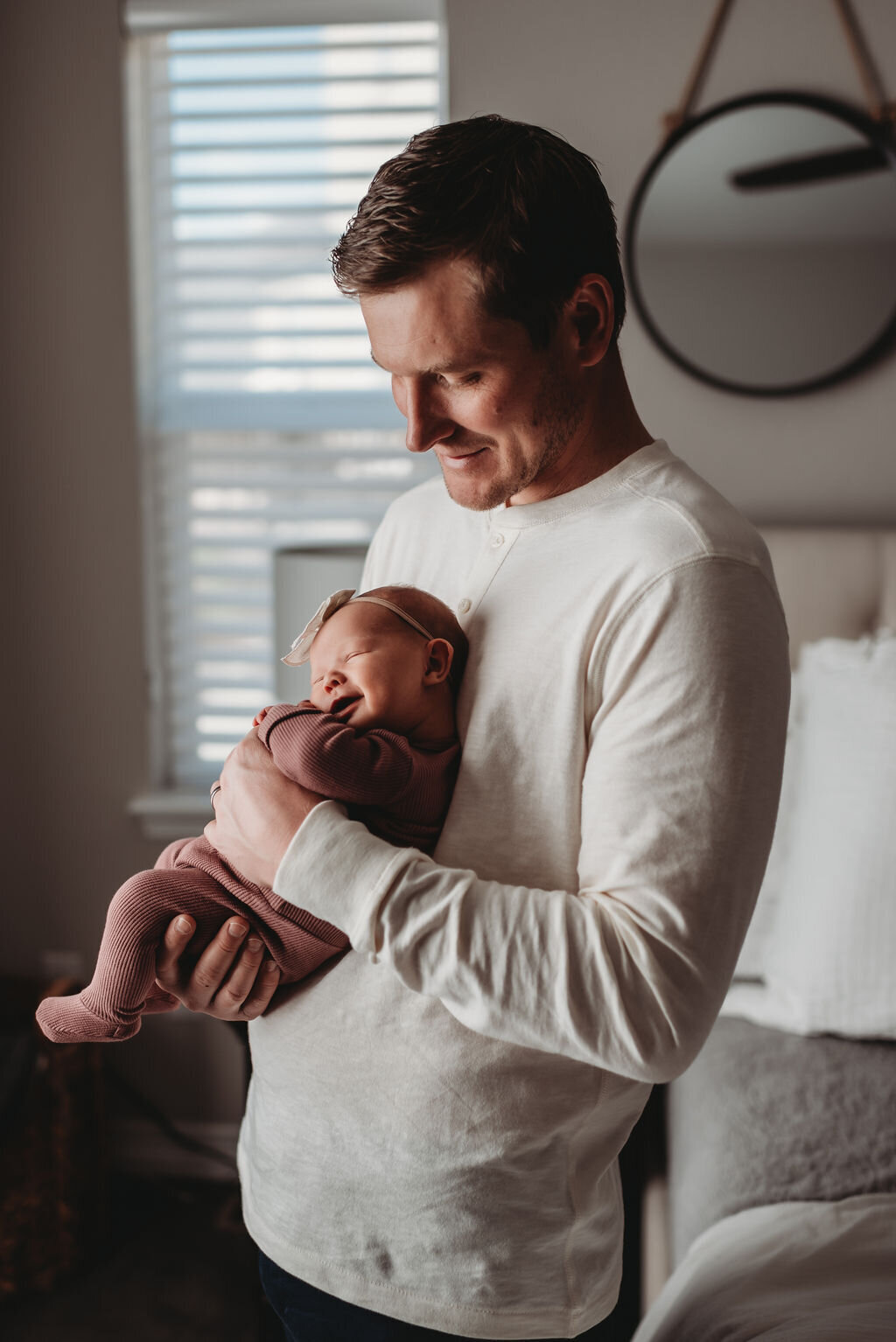 dad holding newborn against his chest while baby smiles
