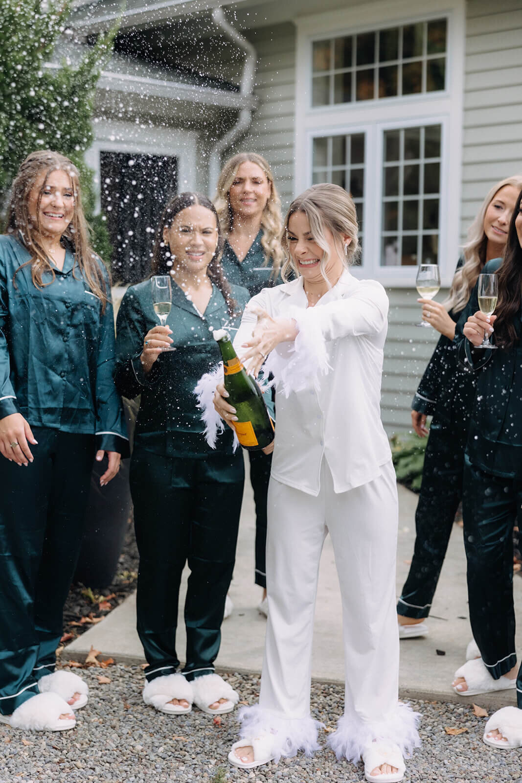Bride popping champagne surrounded by bridesmaids