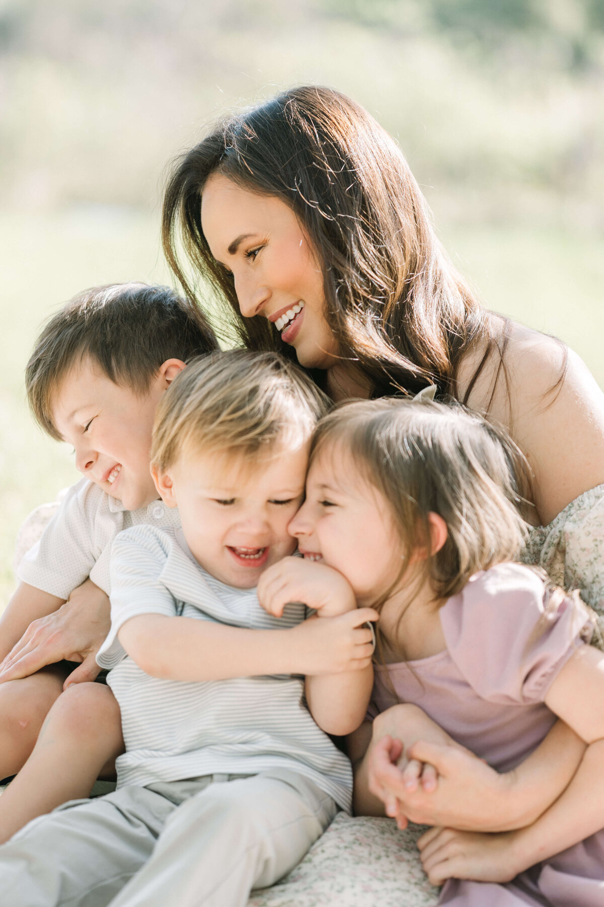 Three young kids snuggle with their mom during outdoor session by Morgan Leigh Photography.