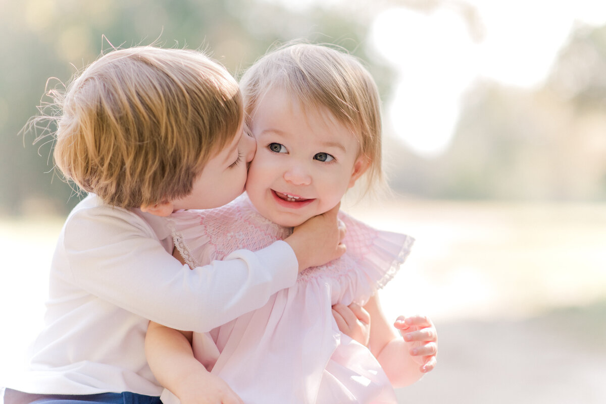 Toddler brother kissing sister for a light and airy portrait