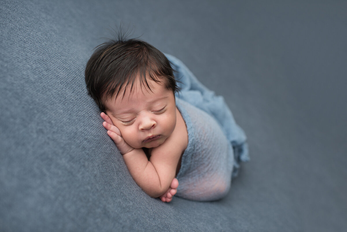 newborn with a navy blue backdrop and blanket