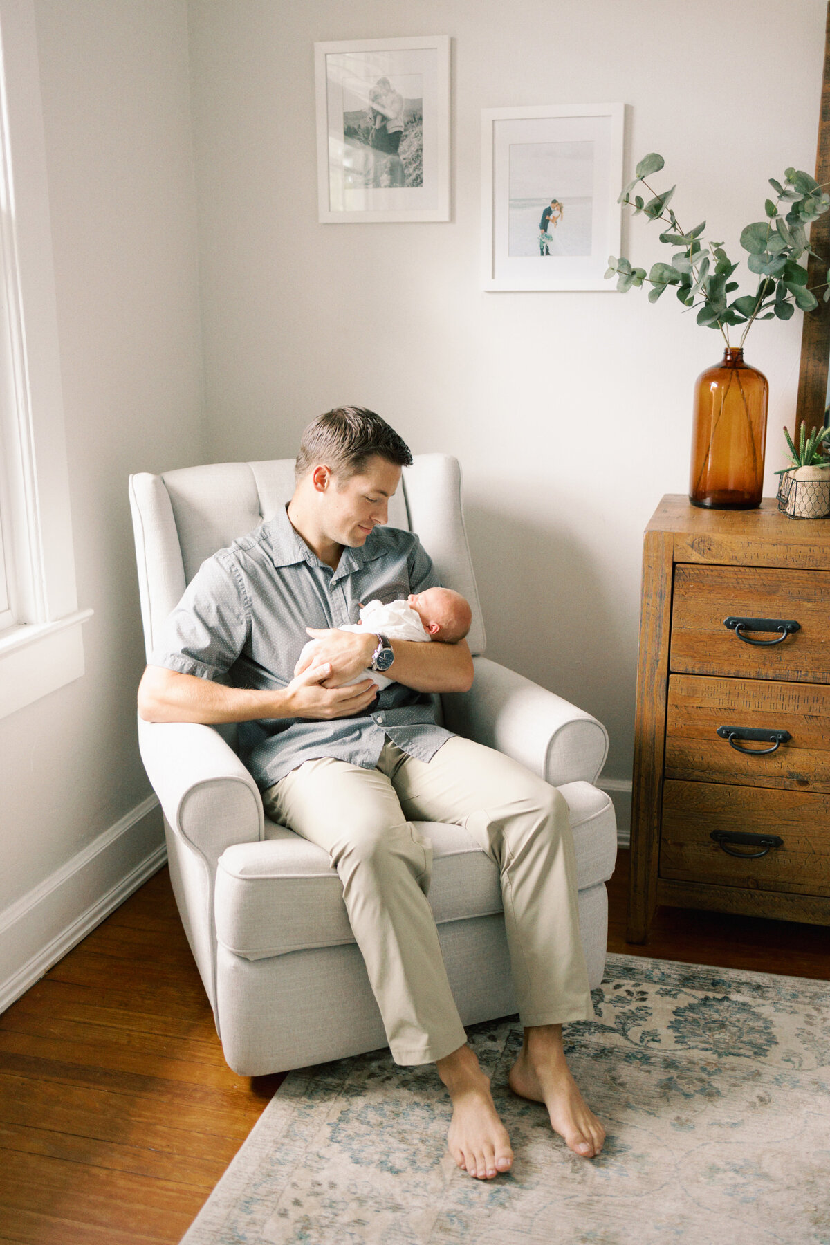 Dad holding newborn baby and rocking baby in a rocking chair in Williamsburg Virginia