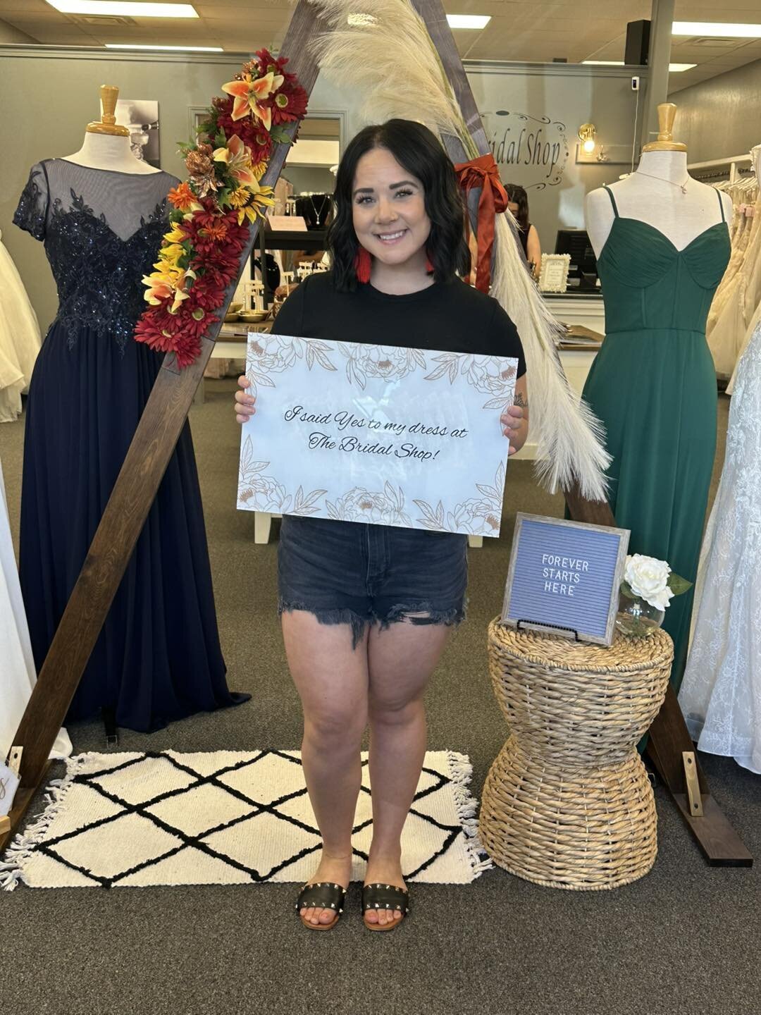 Woman standing in a bridal shop holding a sign after choosing her wedding dress