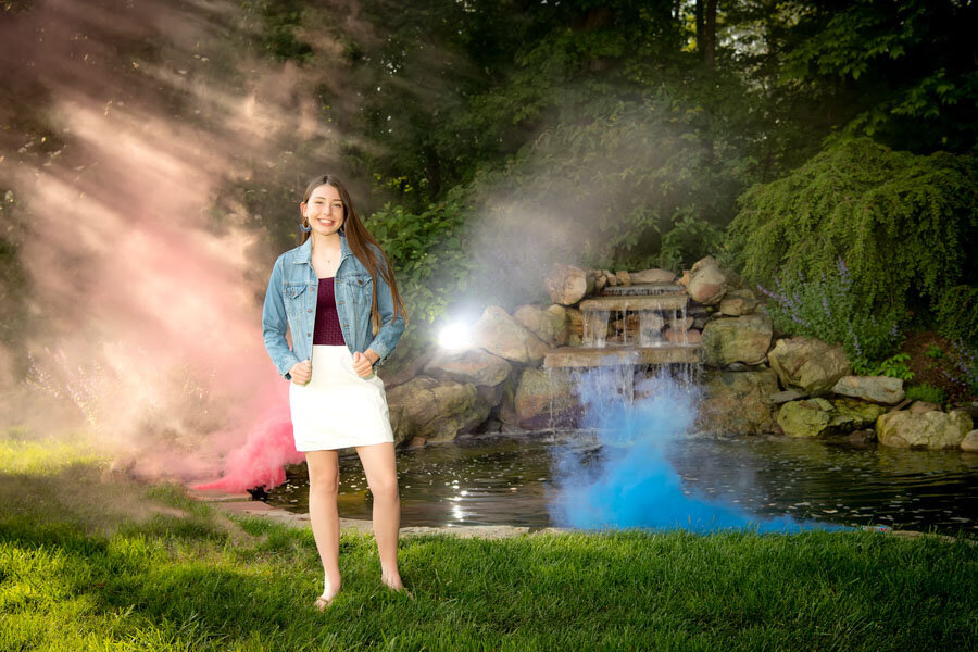 senior girl at waterfall with smoke bombs
