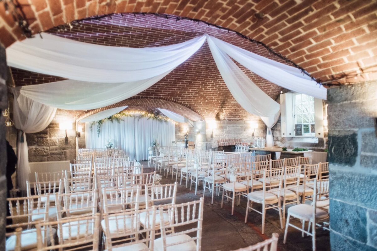 A room filled with lots of white chairs ready for the wedding ceremony