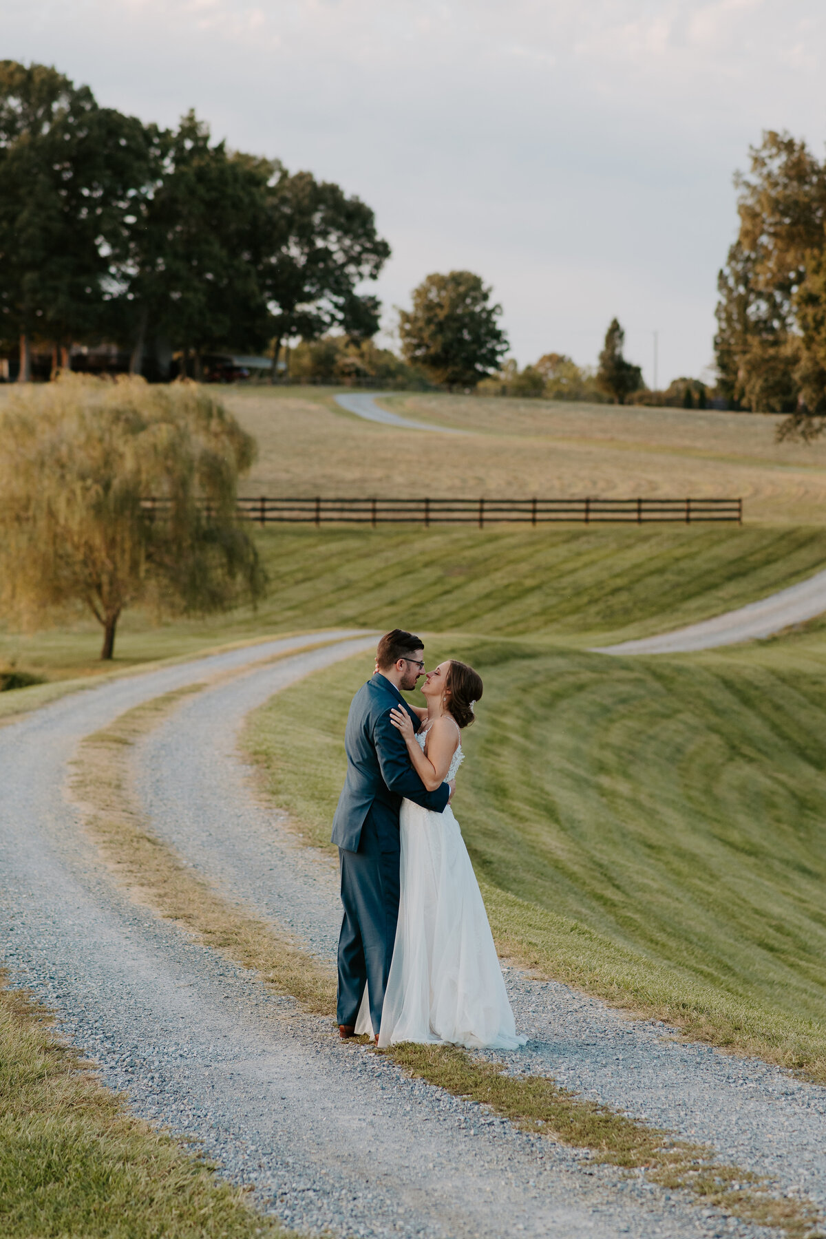 Open field golden hour portraits with the bride and groom, winding road leading down to the couple in the hills of Bedford, Virginia.