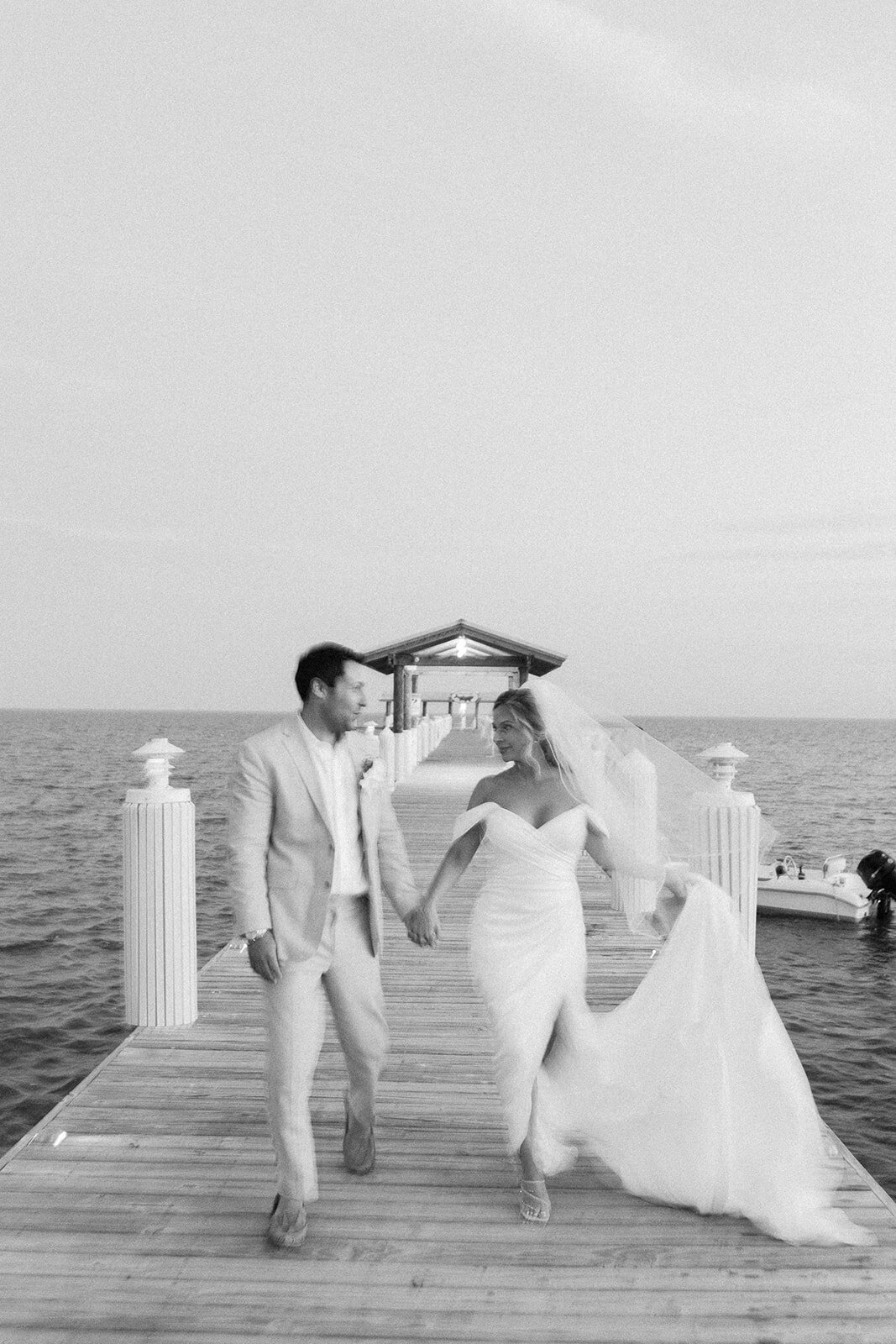 Monica and Austyn share a romantic walk on a wooden pier in the Florida Keys, with the ocean stretching behind them.