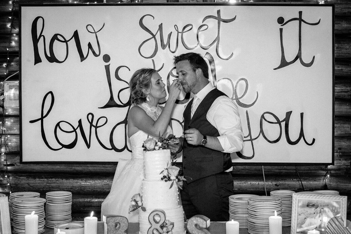 black and white photo of couple feeding each other cake at their wedding in Jackson Hole Wyoming