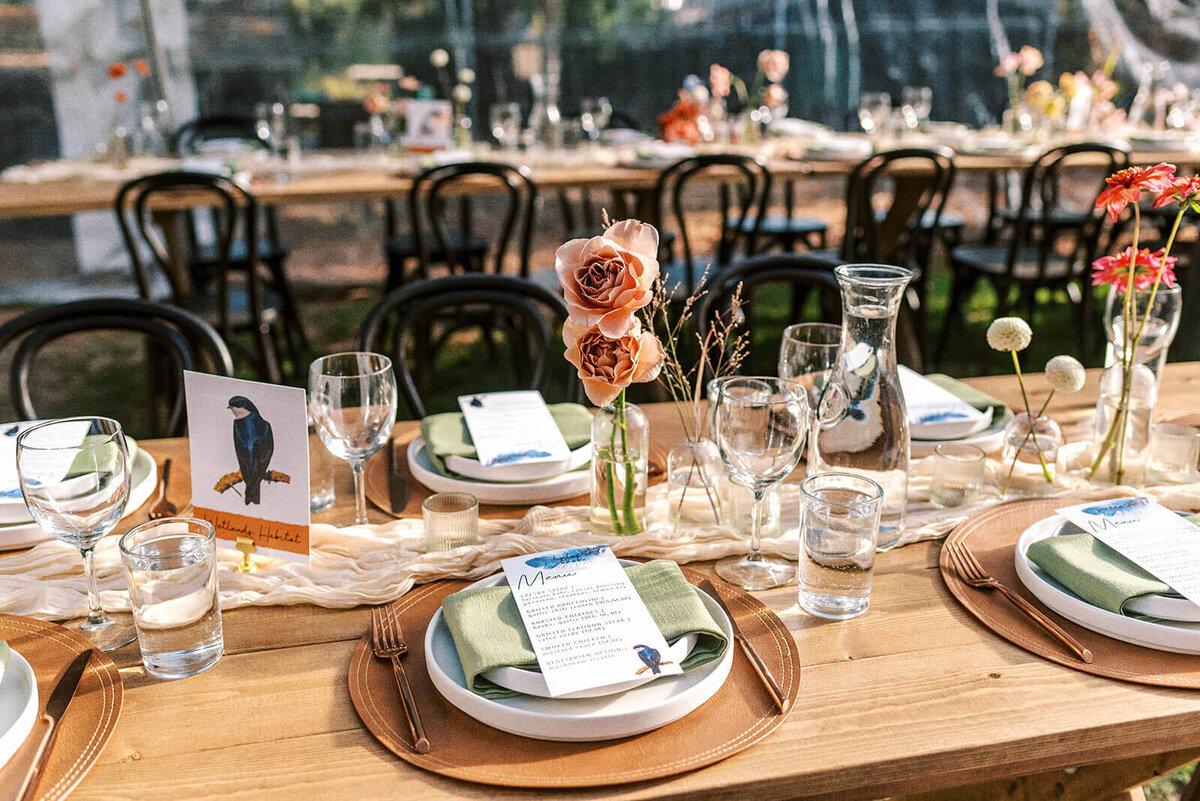 A table setting with tableware, flowers in vases, and menus.