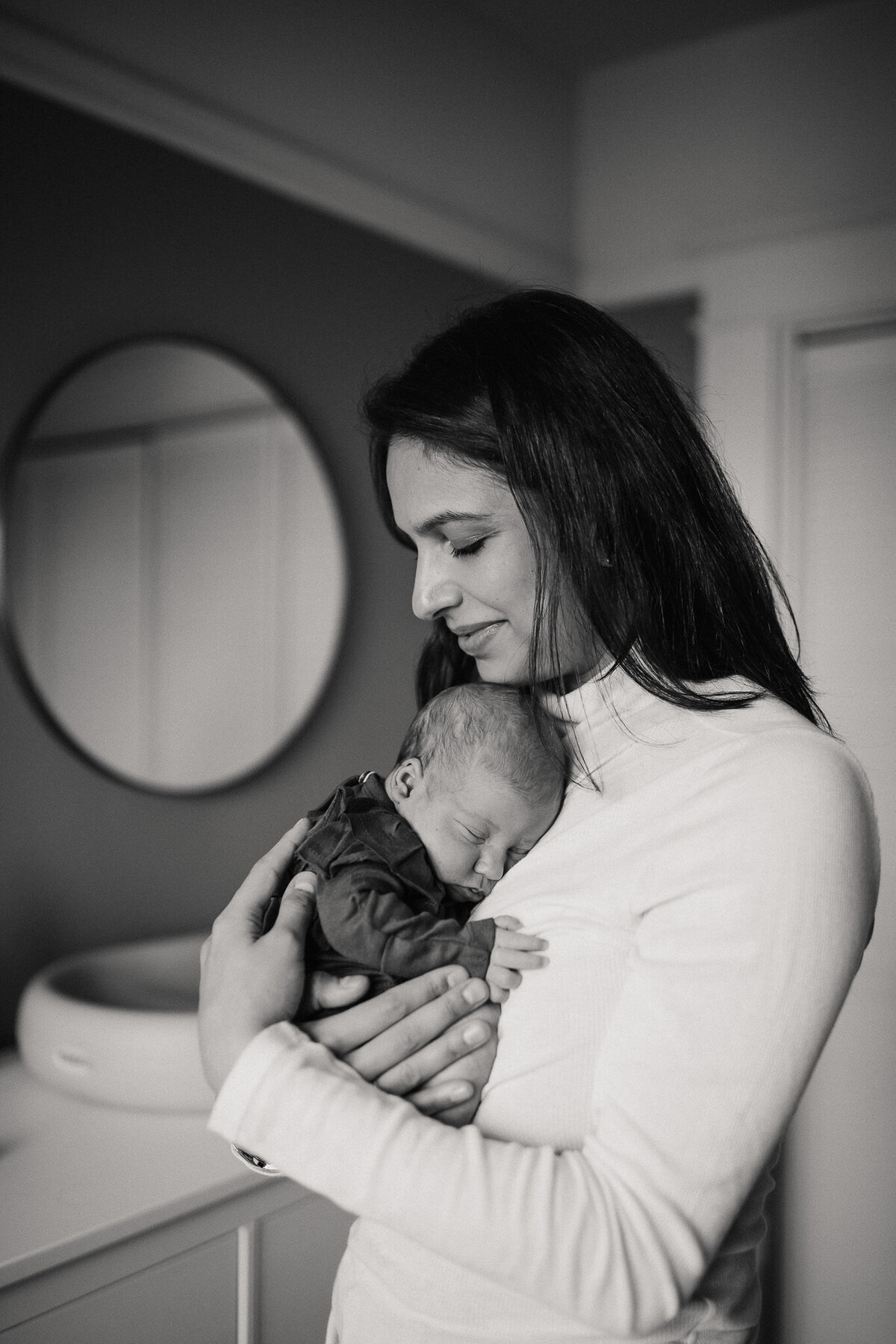 Lifestyle in home newborn session with baby snuggled on mom's chest.