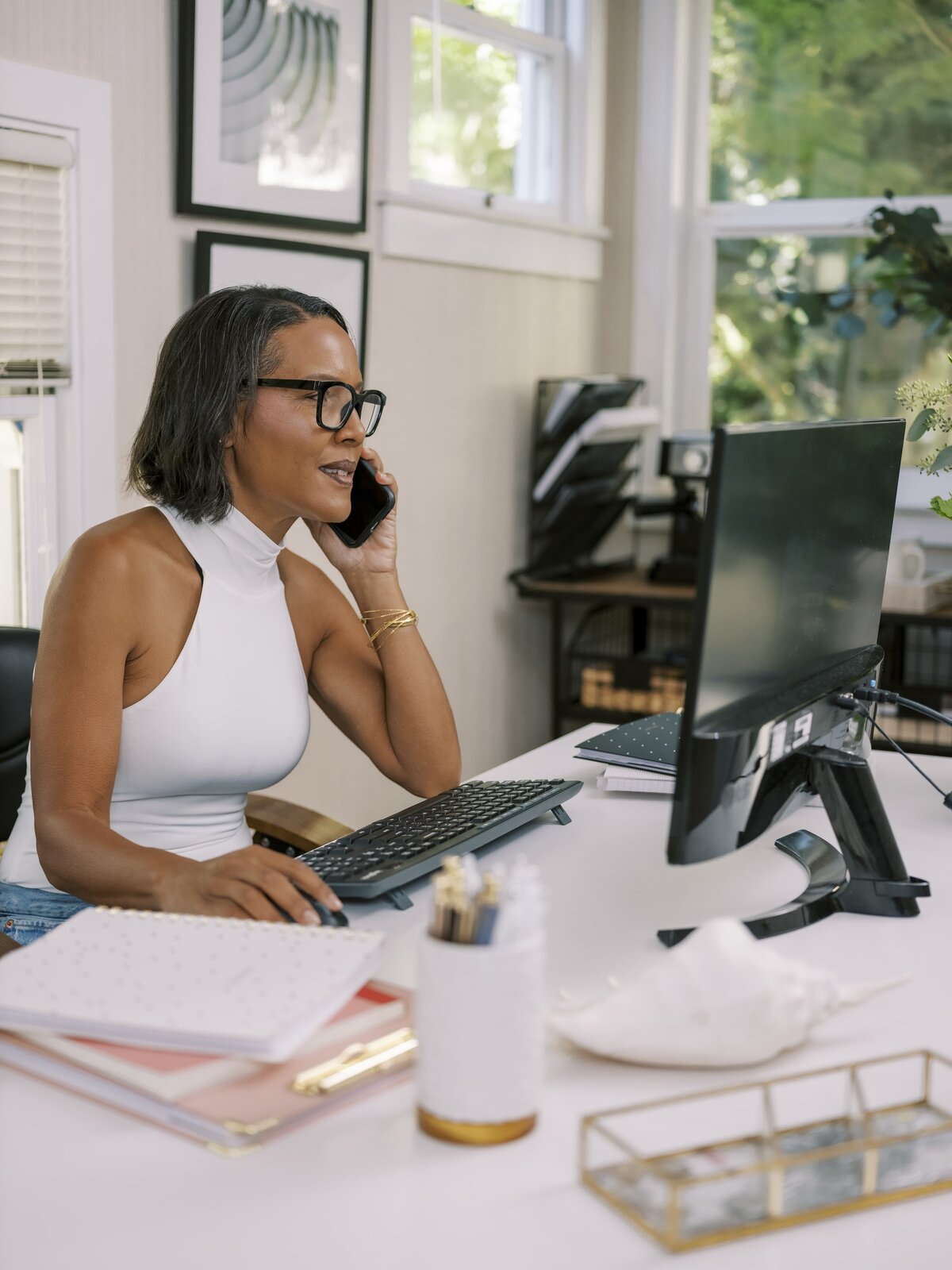 Woman sitting at her desk and computer on her phone