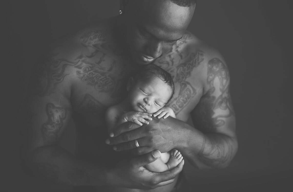 Father holding newborn baby in a black and white image