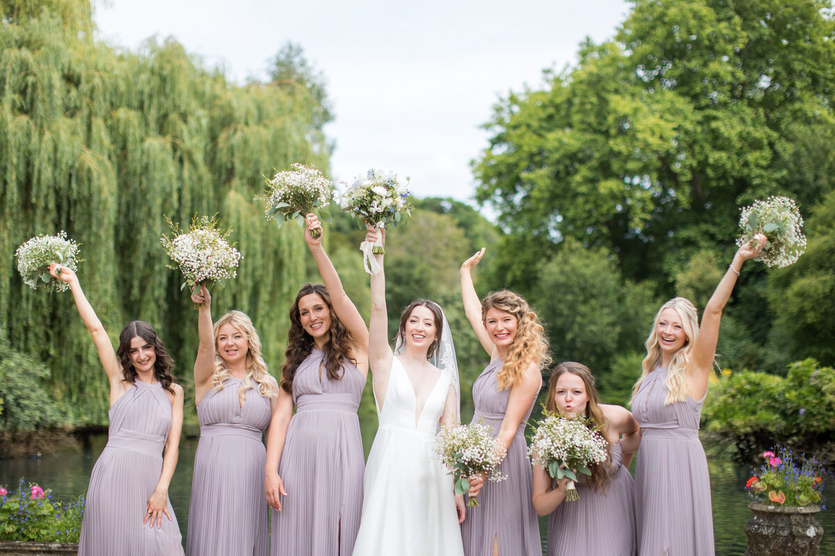 Bridal party in lilac dresses raising bouquets in air