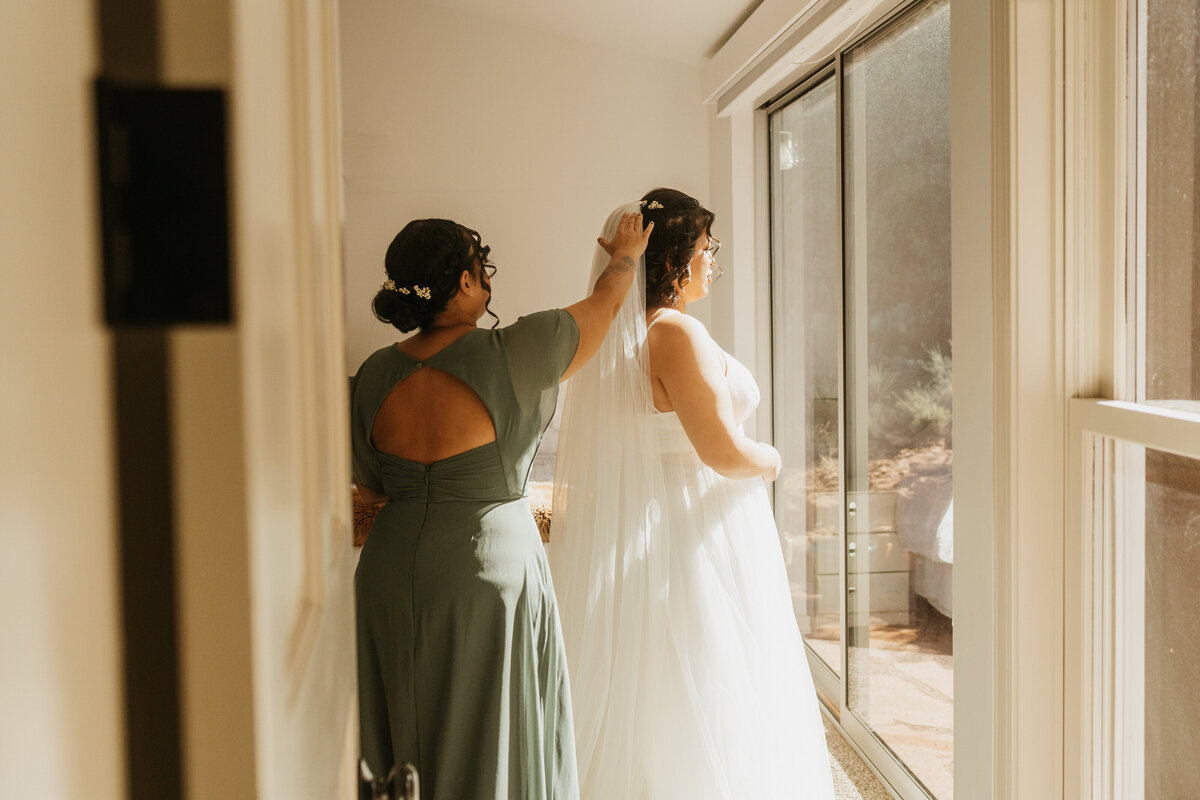 Someone helping to put a veil in someone else's hair 