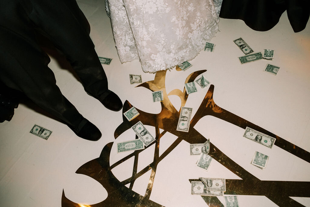 Close up of the brides feet standing on a bunch of dollar bills. 