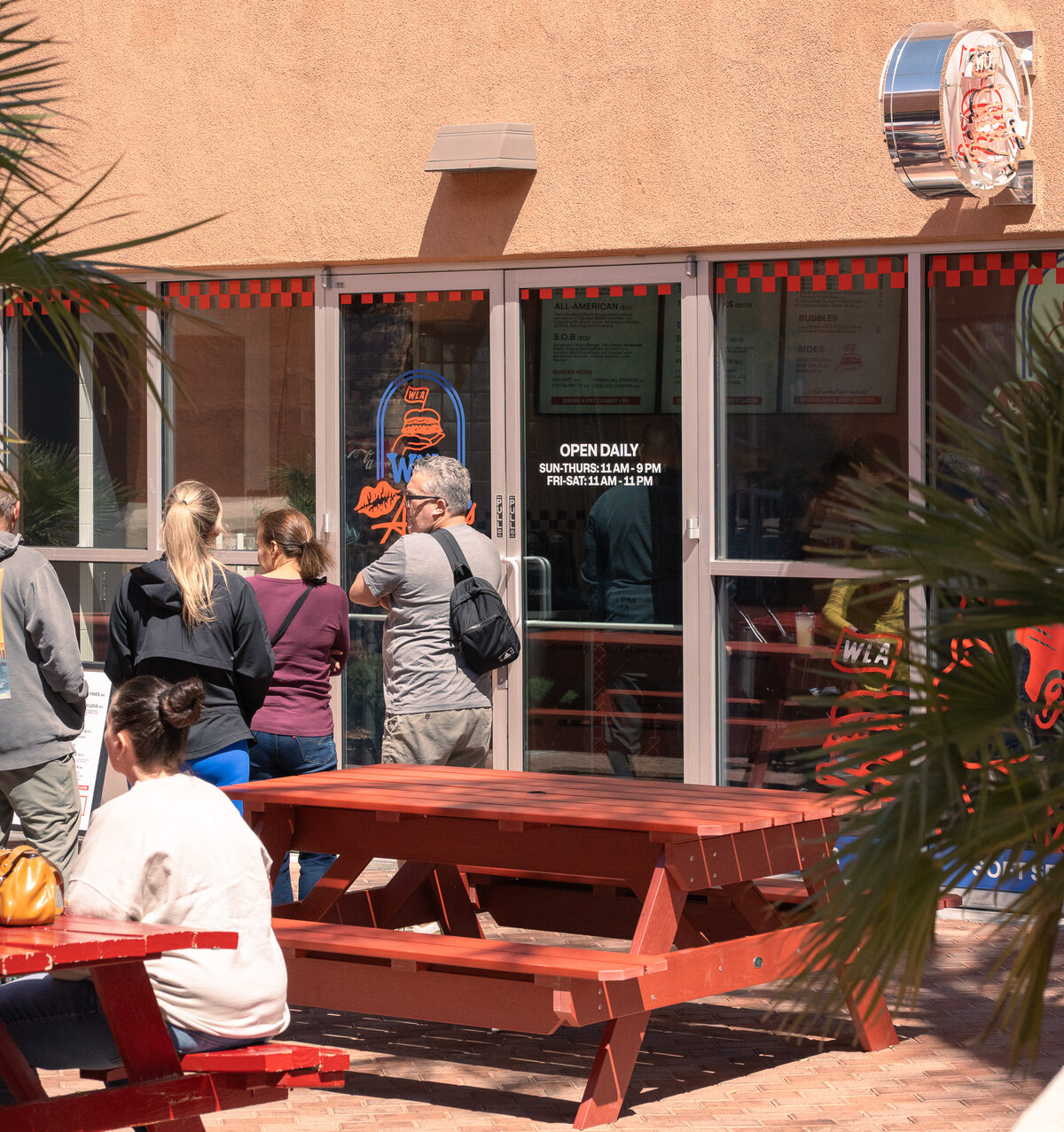 Guests waiting in line outside With Love, Always restaurant in Las Vegas, with red picnic tables and storefront signage visible