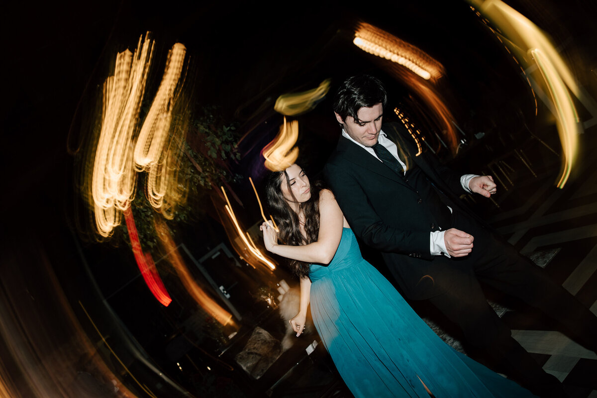 A woman wearing a blue dress and a man wearing a suit dance together with swirls of light around them at The Leona wedding venue in St. Louis during a wedding reception.