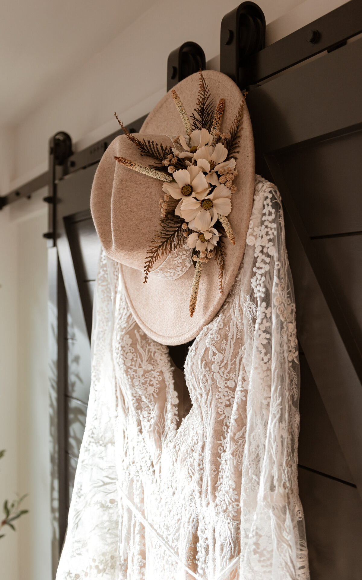 Wedding Dress on Black Indoor Barn Door with Sunbeams Also the Hat is Back
