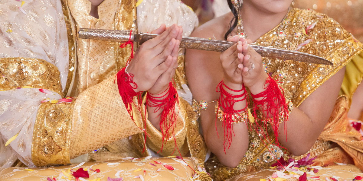 The couple holds their hands together in this traditional pose during their Laos wedding ceremony in Mobile, Alabama.