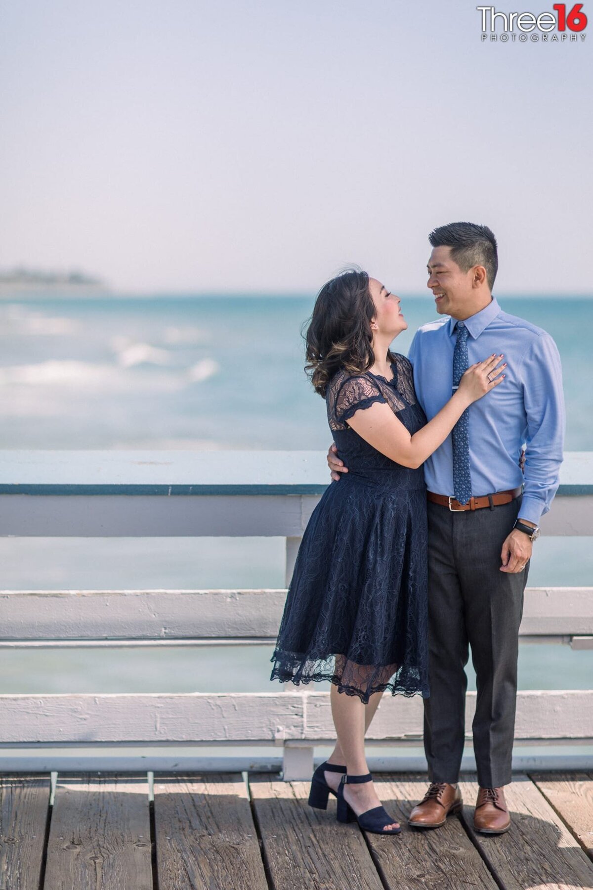 Bride and Groom to be smile at one another while posing on the San Clemente Pier