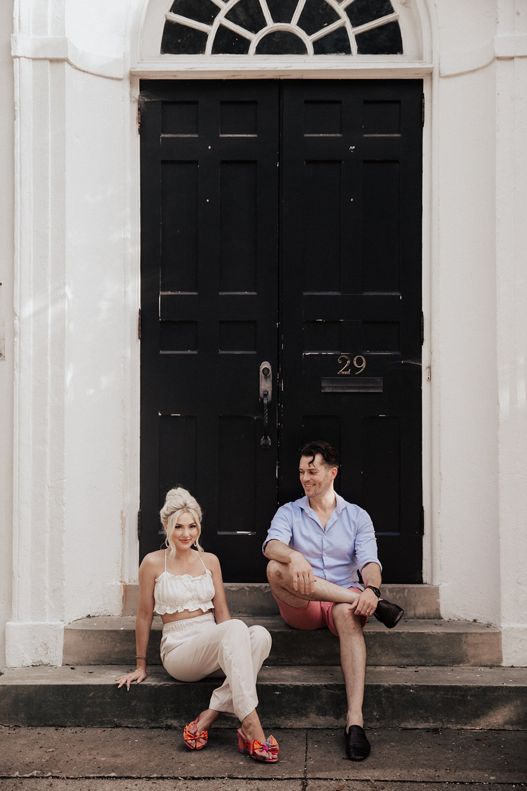 Couple sitting on stairs in front of black Charleston door