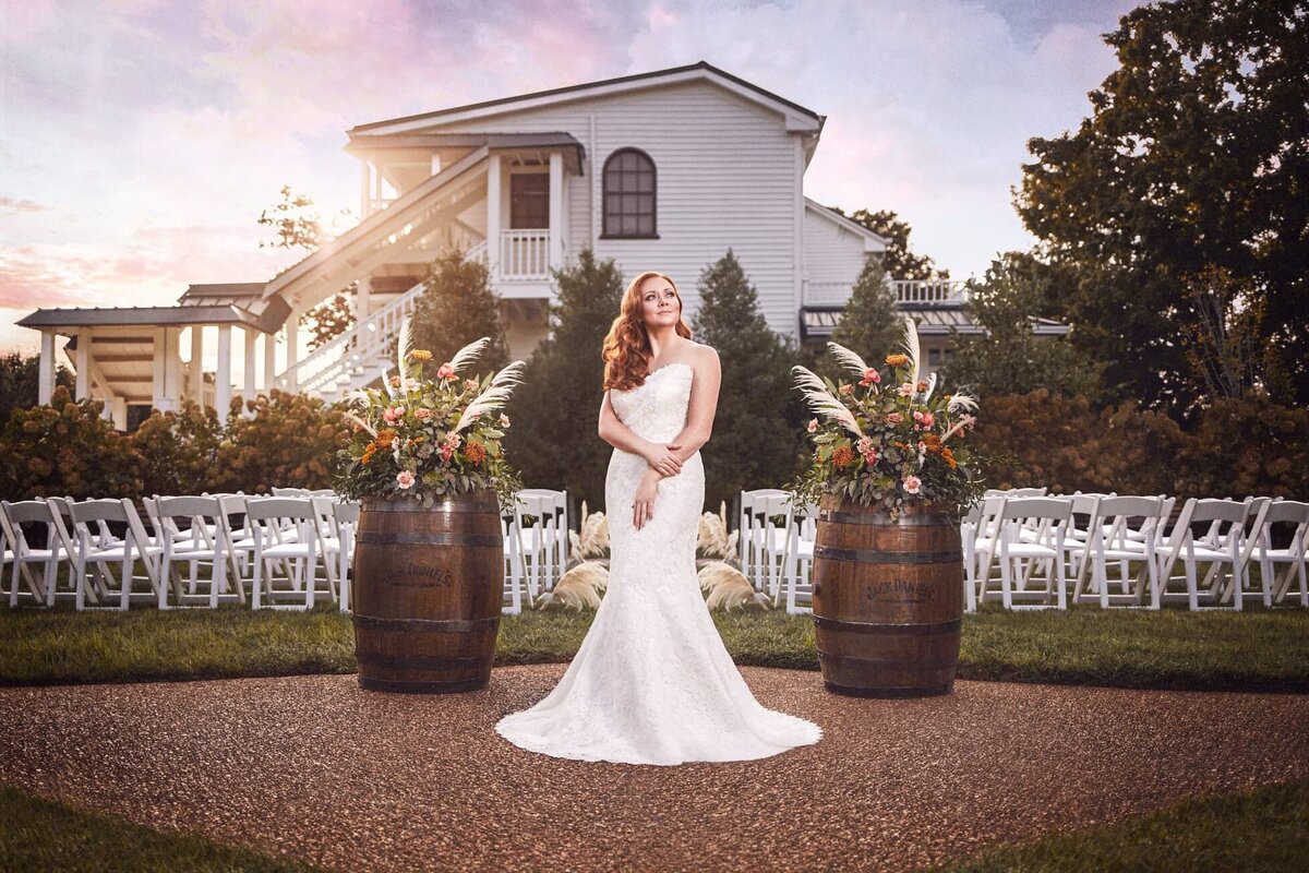 Sunset photo featuring bride standing between two barrel arrangements