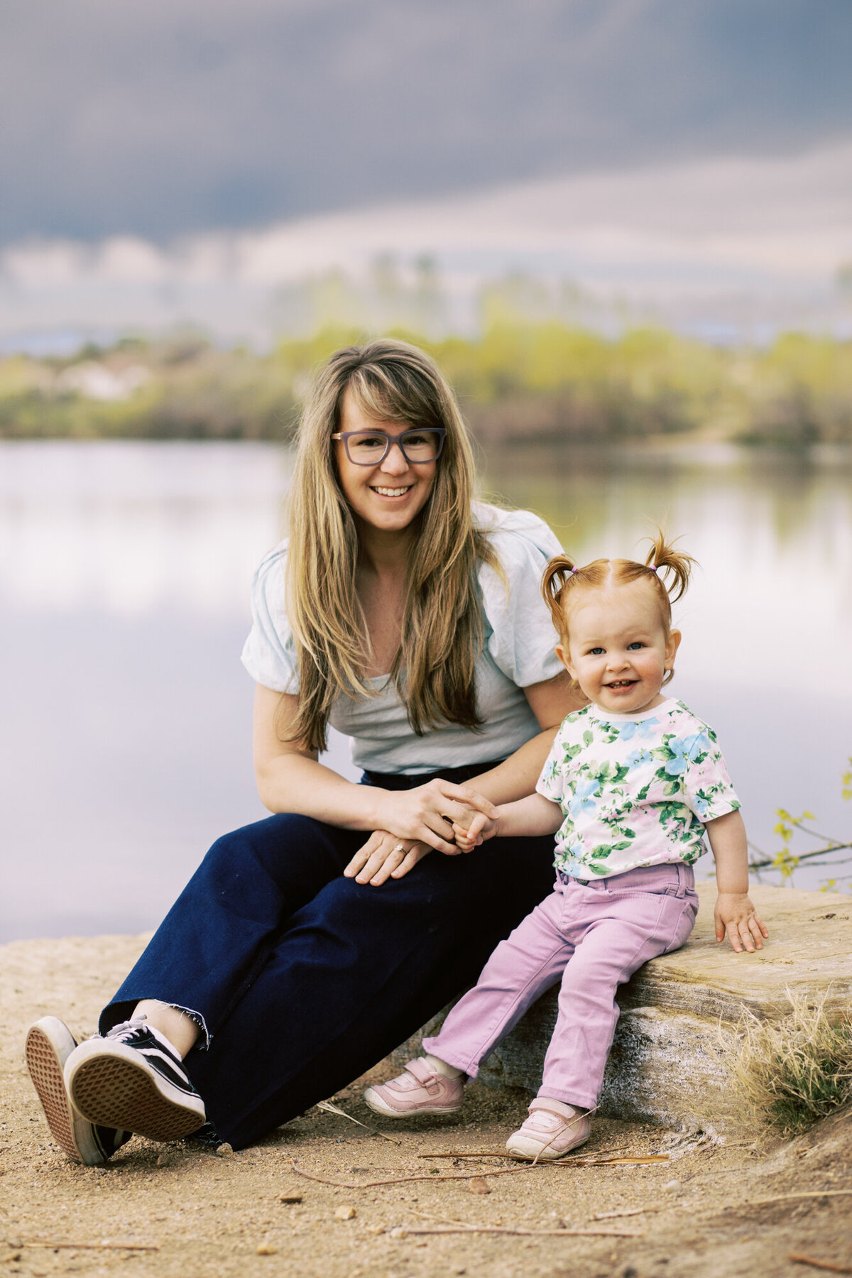 loveland Colorado family portrait with mom and toddler daughter sitting next to each other on a rock in front of a pond