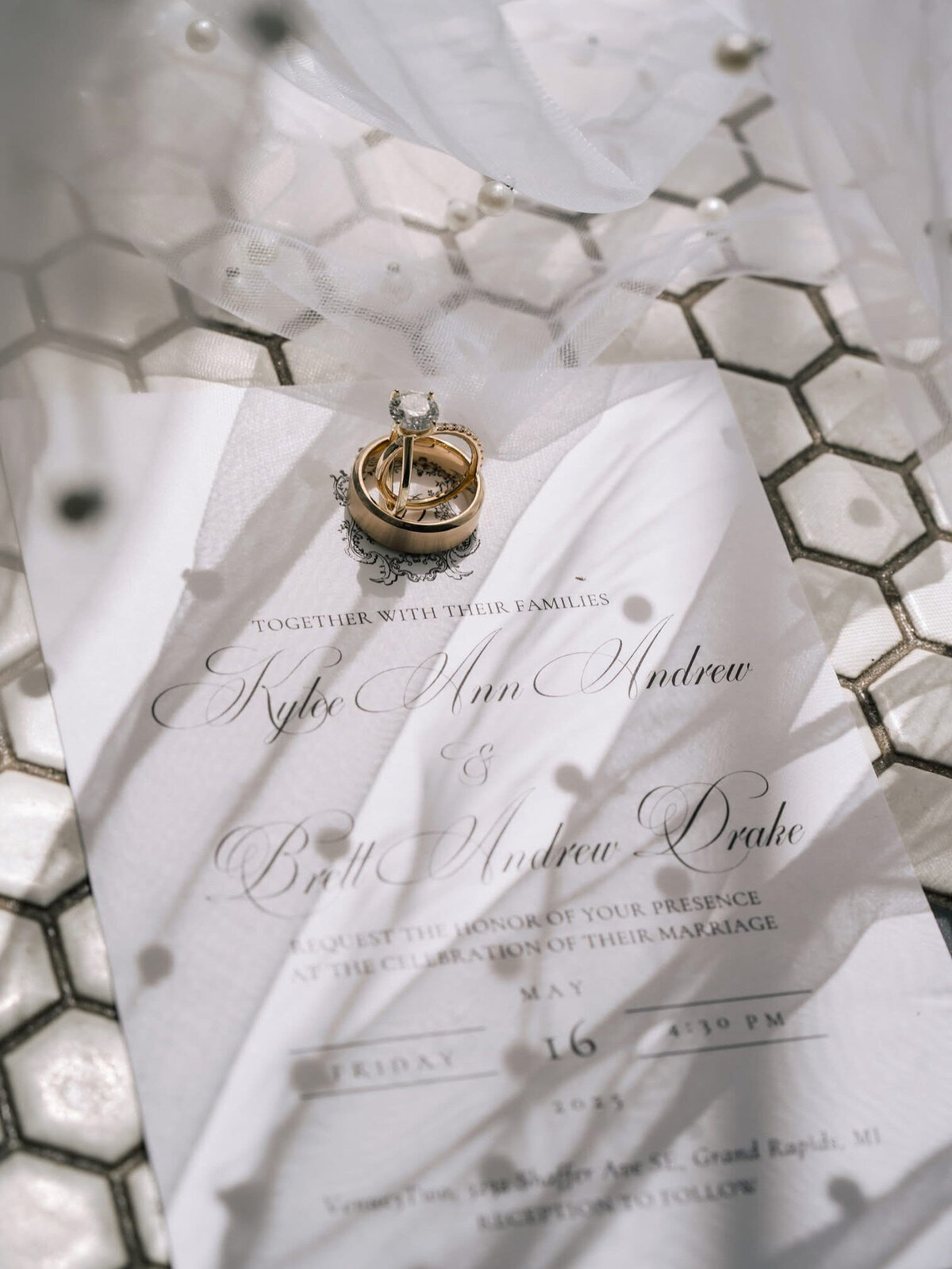 A luxury flat lay of wedding rings and invitation set with shadows and window light