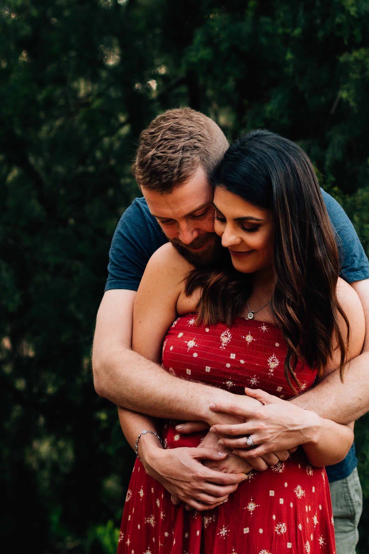 Woman in red dress wrapped in partner's arms, during couple photoshoot Melbourne, And So I Don't Forget Photography