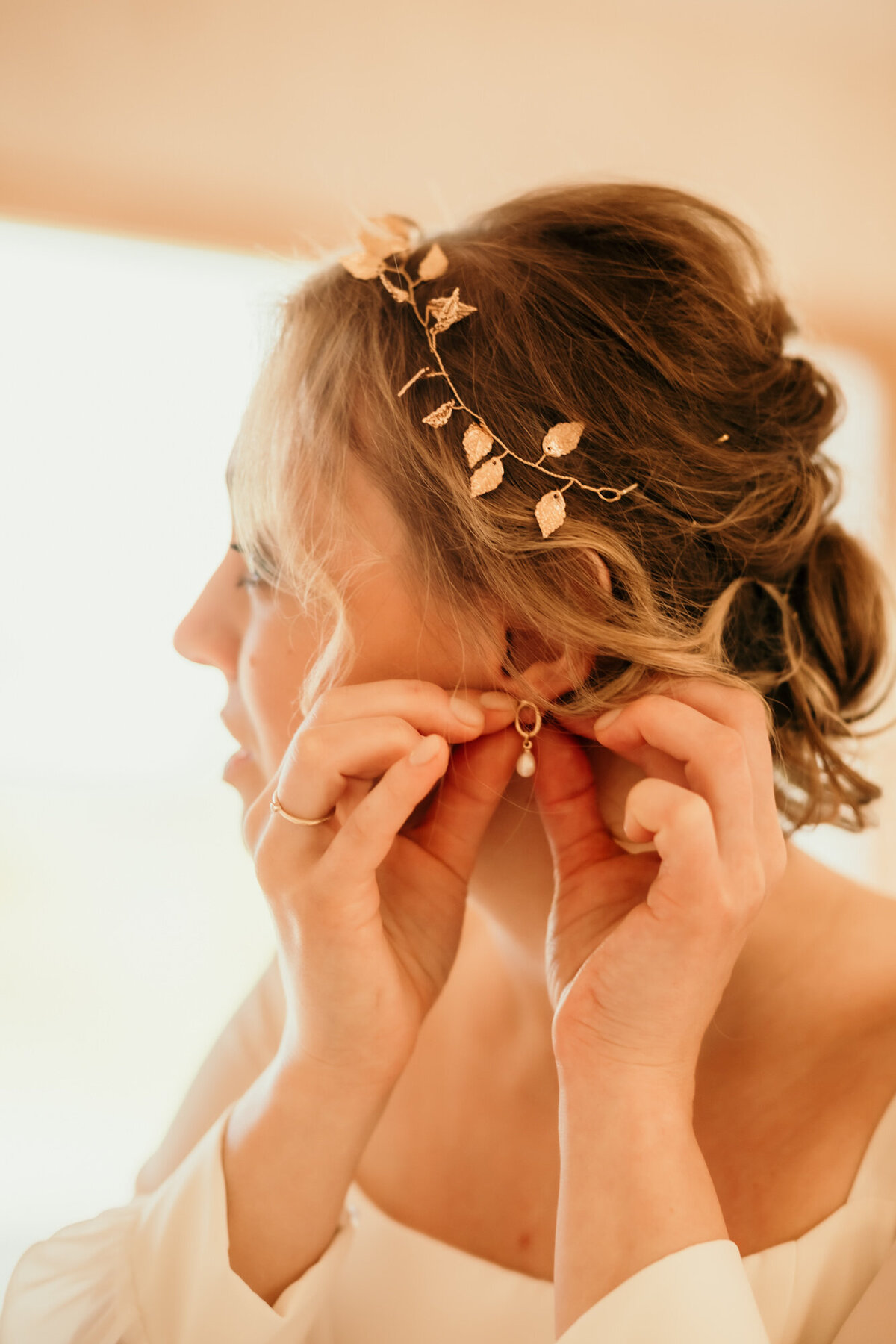 Mit beiden Händen steckt die Braut sich einen Ohrring an.
