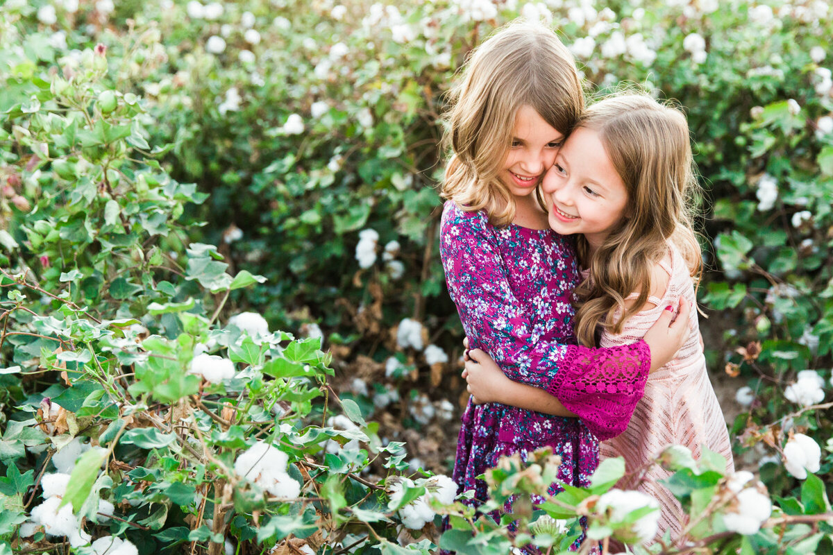 sisters hugging in cotton field