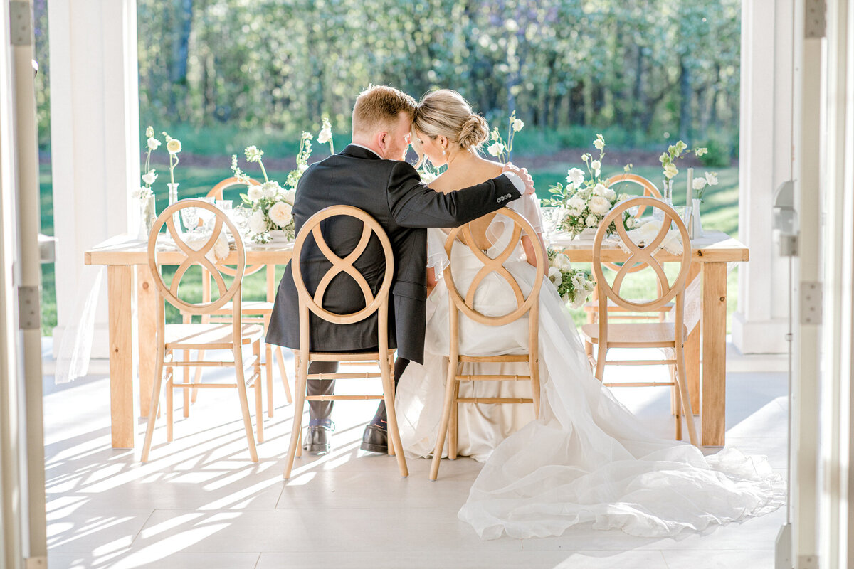 Couple seated at their outdoor reception at Sparrow Lane Events, a sophisticated and romantic wedding venue in Spruce Grove, AB, featured on the Brontë Bride Vendor Guide.