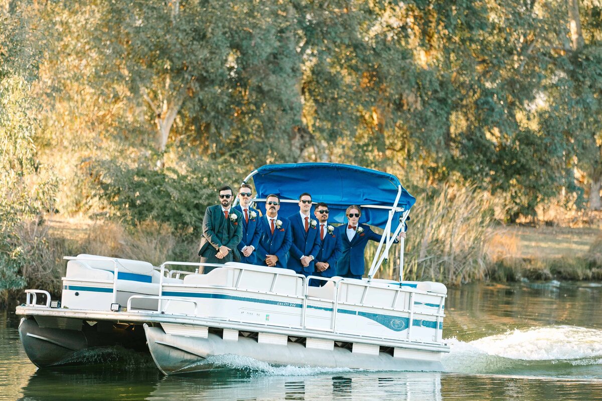 groom and groomsmen arriving on a speed boat on the lake at wolf lakes to begin the wedding ceremony