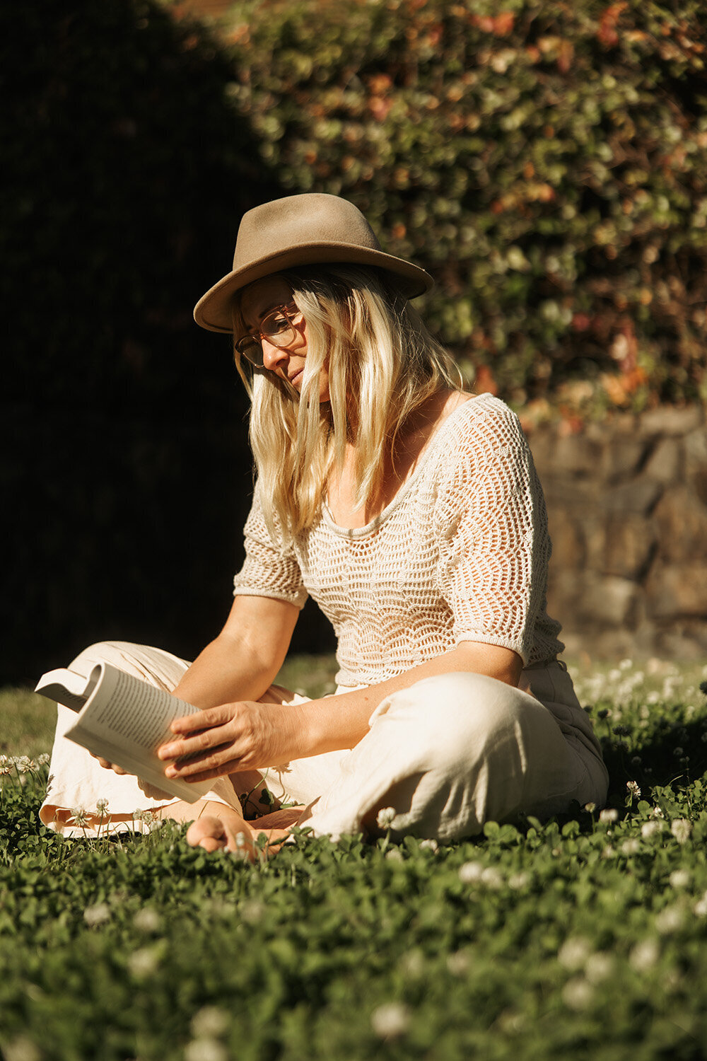 Lady reading a book in the grass at a health and wellness retreat