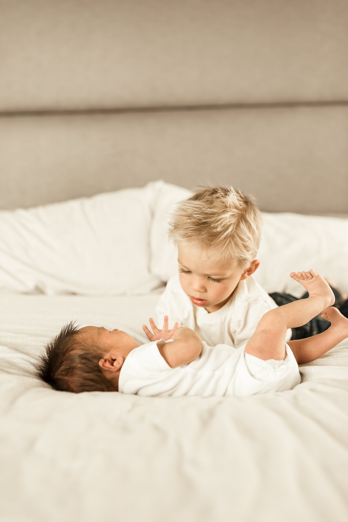 Big brother snuggles with his new best friend on a bed during an in-home newborn photo shoot in Mandan, ND. 