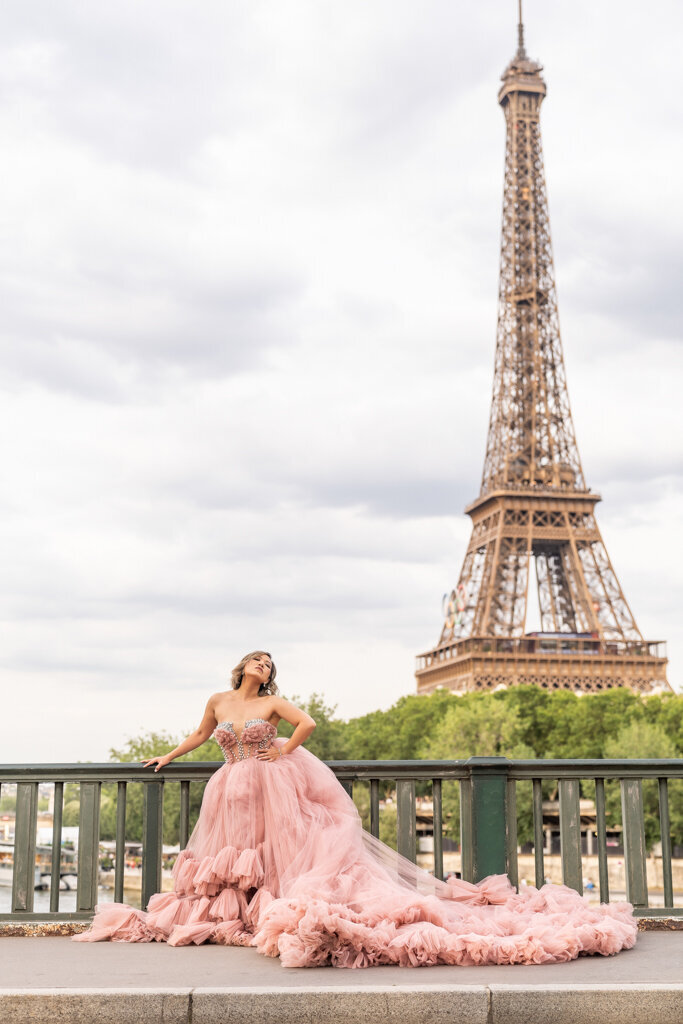 Romantic portrait session on Bir Hakeim bridge featuring woman in powder pink dress with Eiffel Tower backdrop