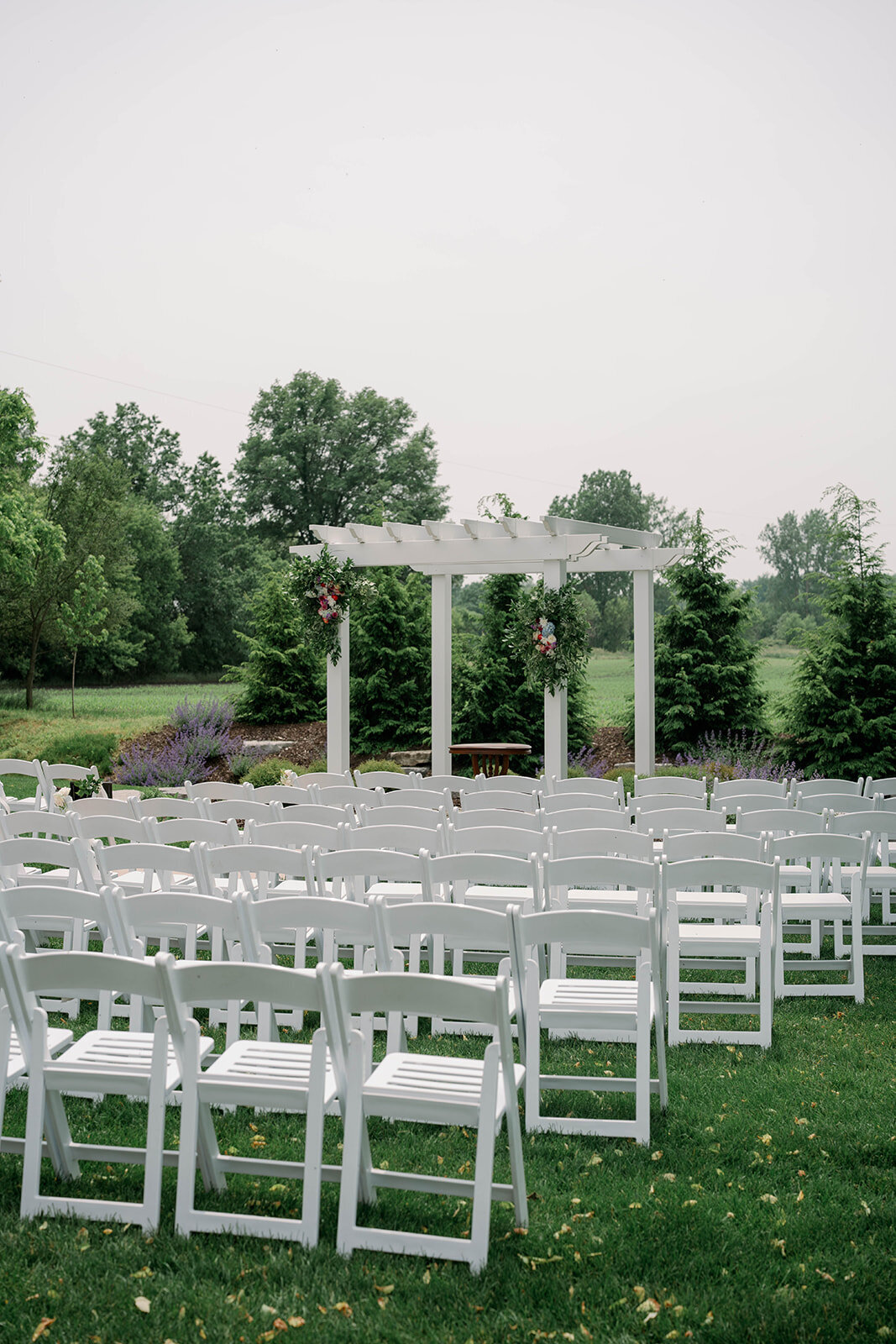 Wide photo of the empty outdoor ceremony space at The Blue Heron Barn wedding venue in Kalamazoo, Michigan, featuring rustic wooden chairs and countryside views.