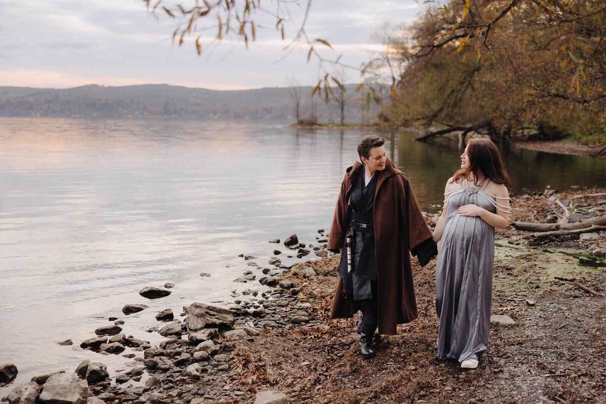 Couple walking along by lake for maternity photo session in Fingerlakes, NY