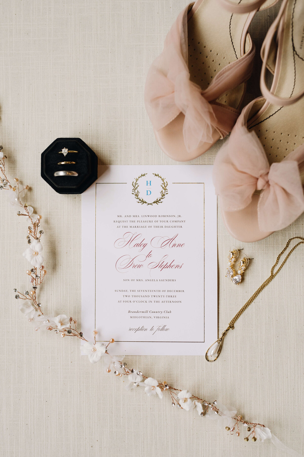 wedding day flatlay to show details of an elegant wedding decor and bridal details with a wedding invitation in the middle with the brides pink shoes and elegant jewelry surrounding it