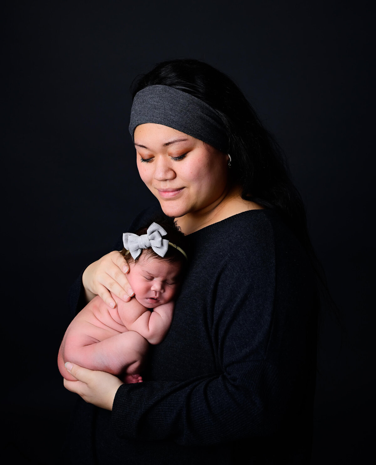 Low key lighting for a newborn photoshoot with mom holding her newborn baby. Image by Kitsap Peninsula  photographer E. Benecki Photography.